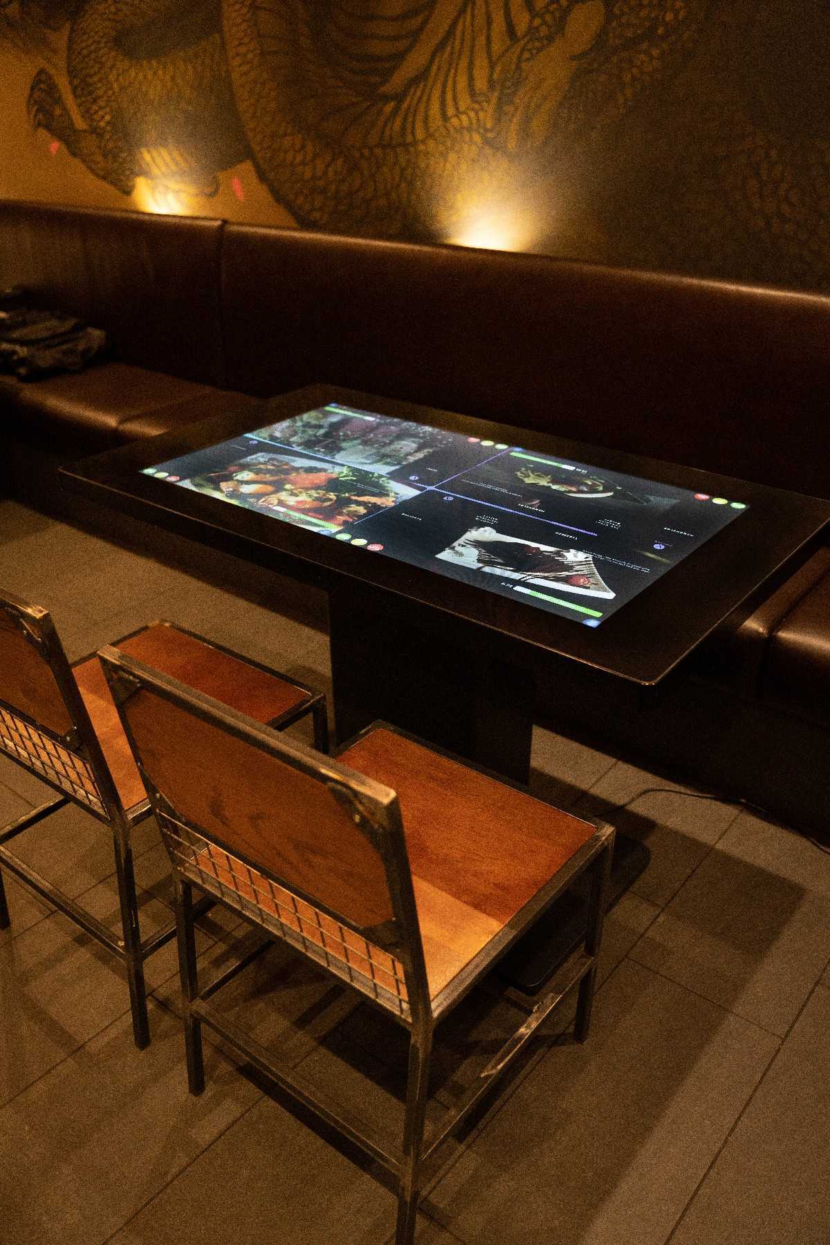 Interactive touchscreen dining table installed in a restaurant, displaying a digital ordering interface.